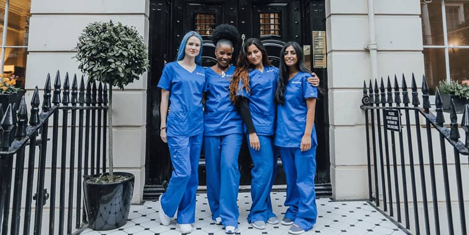 Four nurses in blue scrubs outside a Georgian clinic entrance for Exion body contouring in Dublin